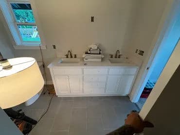 Modern bathroom with double sink vanity, neutral tiles, and natural light.